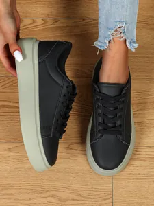 Nahaufnahme schwarzer Plateau-Sneaker mit dicker Sohle und Distressed-Jeans