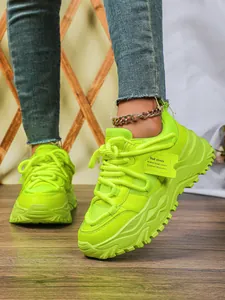 Detailopname van neongroene chunky sneakers met platformzool, mesh en dikke zool.