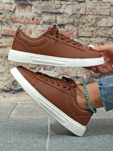 Vista laterale di sneaker casual da donna in pelle marrone con suole bianche spesse.