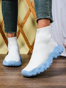 Detail van witte ademende gebreide sok-sneakers met een blauwe golvende dikke zool