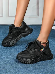 Dettaglio delle sneakers chunky nere con inserti in mesh traspirante su un tappeto blu