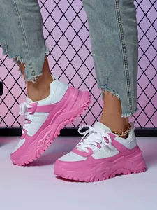 Close-up of pink and white chunky dad sneakers worn with distressed denim jeans.