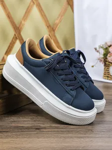 Zijaanzicht van marineblauwe damesplateausneakers met dikke witte zolen en bruine hielen