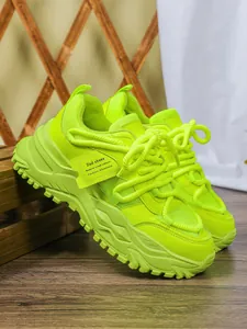 Detail van levendige neongroene chunky dad-schoenen met mesh en getextureerd leer