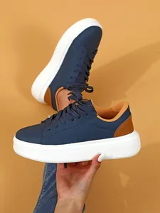 Detailansicht der dunkelblauen Plateau-Sneaker mit dicker weißer Sohle und braunem Besatz