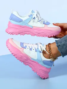 Close-up detail of chunky pastel sneakers featuring thick pink soles and white laces