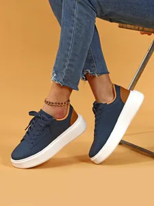 Nahaufnahme von dunkelblauen Plateau-Sneakern für Damen mit weißen Sohlen und Jeans.
