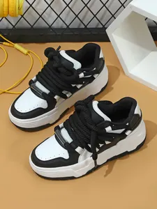 Detalle de zapatillas de plataforma gruesa en blanco y negro con cordones de cuerda.