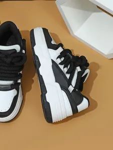 Detalle de zapatillas de plataforma blancas y negras con cordones gruesos tejidos.