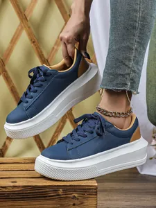 Detailopname van marineblauwe platform sneakers met witte zolen en bruine accenten.
