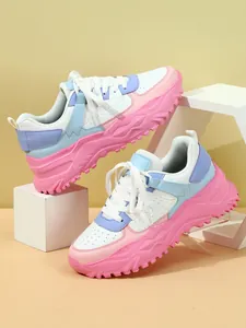 Close-up of white, pink, and blue chunky sneakers on geometric display props