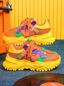 Vista dettagliata di scarpe chunky vivaci arancio e giallo su sfondo creativo colorato