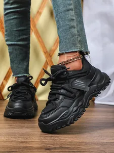 Detailopname van zwarte chunky sneakers met mesh en modieuze dikke zolen aan model