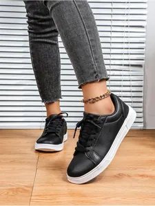 Primo piano di sneakers da skateboard casual nere con spessa suola bianca su pavimento in legno