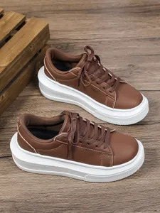 Gedetailleerd zicht op bruine platform sneakers met dikke witte zool op hout.