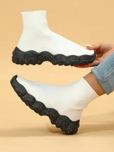 Detail van ademende witte gebreide sok-sneakers met dikke zwarte gespikkelde zool
