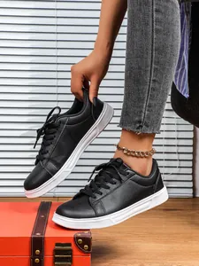 Sneaker basse nere classiche con suole bianche spesse su una valigia vintage di colore arancio.