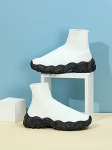 Gedetailleerd beeld van witte gebreide sok-sneakers met dikke zwarte zolen