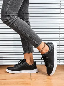 Dettaglio laterale di sneaker nere con suola platform bianca su pavimento in legno