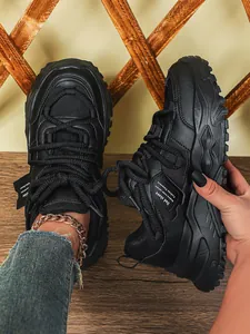 Detailopname van zwarte chunky Dad-sneakers met ademend mesh en een dikke plateauzool