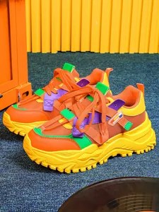 Dettaglio di sneaker chunky arancioni con suola gialla spessa e accenti viola