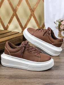 Detailopname van bruine dames sneakers met dikke witte platformzolen op houtblok.