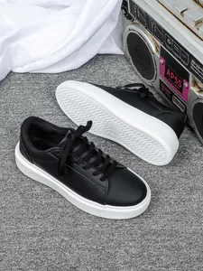 Klassische schwarze Low-Top-Sneaker mit dicker weißer Plateausohle und Schnürung