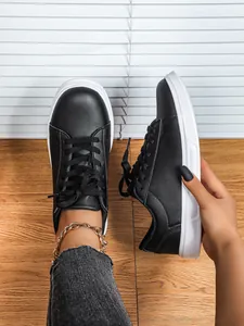 Vista dettagliata di sneaker platform nere alla moda con suole bianche e lacci neri classici