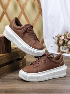 Gedetailleerde opname van bruine plateau sneakers van kunstleer met dikke witte zolen.