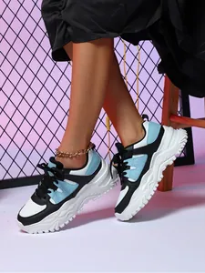 Detail of breathable chunky sneakers in white, black and blue worn with an anklet.