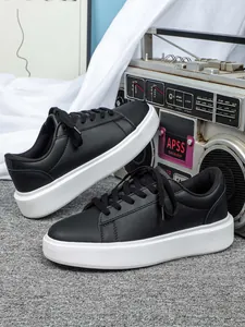 Klassische schwarz-weiße Plateau-Sneaker mit dicker Sohle vor einem Retro-Radio-Hintergrund