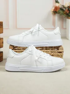 Sneaker basse bianche minimaliste con texture in pelle pulita e suola morbida.