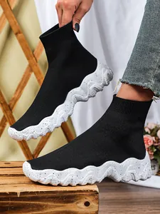 Gedetailleerde weergave van zwarte gebreide sok-sneakers voor dames met dikke witte zolen.