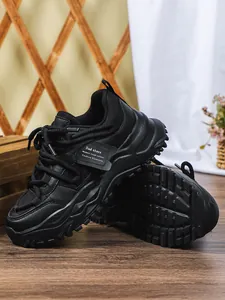 Close-up van zwarte chunky dad-sneakers met plateauzool en getextureerd leer en mesh