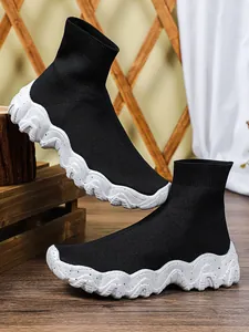 Detail van zwarte gebreide sok-sneakers met dikke gespikkelde witte zolen.