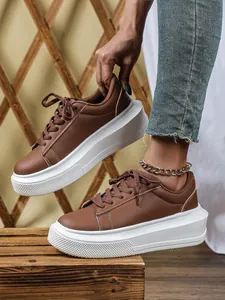 Detailweergave van bruine damesplatformsneakers met dikke witte zool