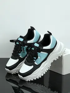 Modern chunky platform sneakers in black and light blue on a professional display.