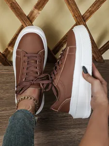 Detailweergave van bruine plateau-sneakers met dikke witte zolen en vetersluiting.
