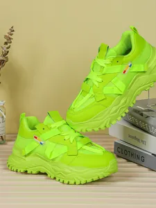 Vista laterale dettagliata di sneakers chunky con zeppa verde lime su libri decorativi