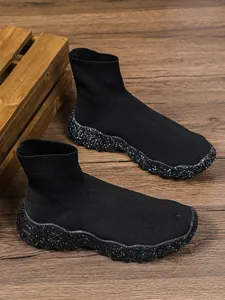 Gedetailleerd zicht op zwarte halfhoge sok-sneakers met gespikkelde plateauzolen