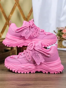 Zijprofiel detail van trendy roze chunky dad sneakers met dikke plateauzool en mesh stof.