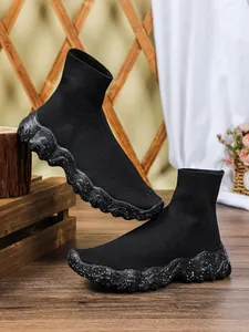Zijaanzicht van zwarte gebreide sok-sneakers met wit gespikkelde dikke plateauzolen