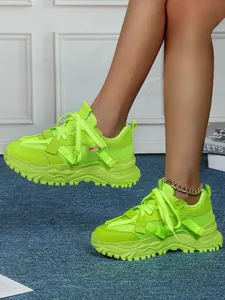 Dettaglio di sneakers chunky verde neon con suola spessa e mesh tecnico traspirante.