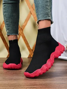 Gedetailleerd overzicht van zwarte gebreide sneakers met een dikke roze golfzool