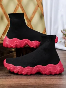 Gedetailleerd beeld van ademende zwarte gebreide sok-sneakers met dikke roze zolen