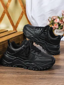 Close-up of black chunky sneakers featuring a thick textured sole for a stylish casual look