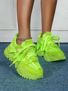 Primo piano di sneakers platform verde neon su tappeto blu per moda donna calzature