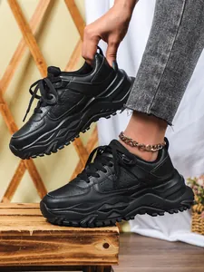 Close-up detail of black chunky platform sneakers with textured wave-patterned soles.