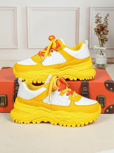Close-up of vibrant yellow and white chunky dad sneakers displayed on a suitcase
