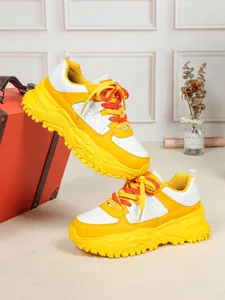 Detailed shot of chunky yellow and white sneakers with platform soles for casual style.
